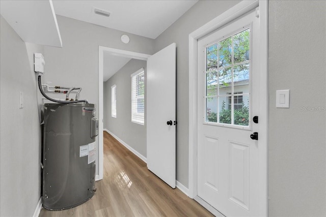 doorway to outside featuring electric water heater and light hardwood / wood-style flooring