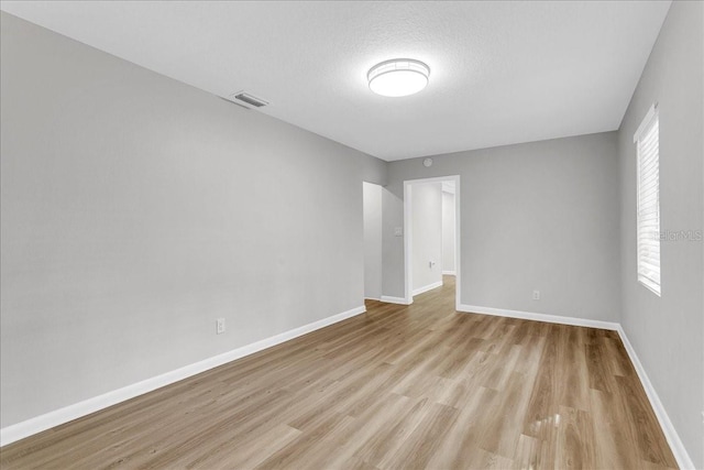 unfurnished room featuring a wealth of natural light, a textured ceiling, and light hardwood / wood-style floors