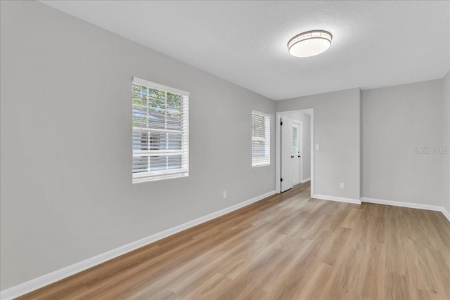 unfurnished room featuring light wood-type flooring and a textured ceiling