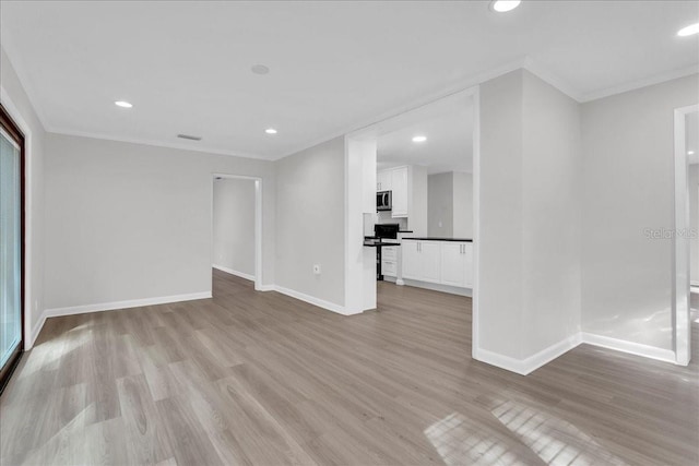 empty room with light wood-type flooring and crown molding