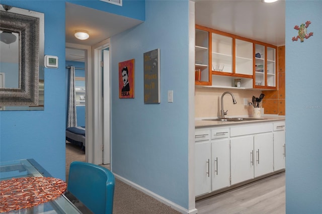 kitchen with white cabinets, sink, and light hardwood / wood-style flooring