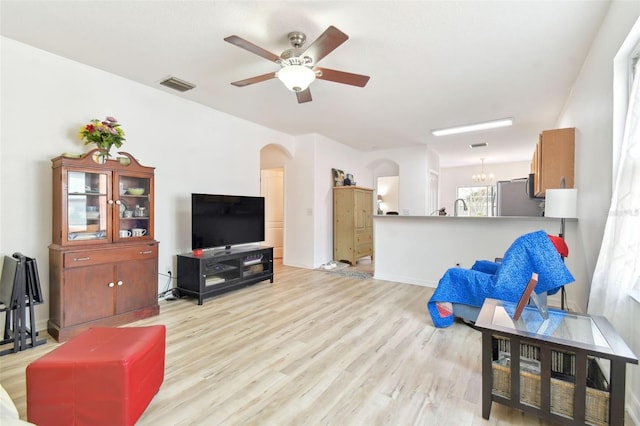 living room featuring ceiling fan with notable chandelier, light hardwood / wood-style floors, and sink