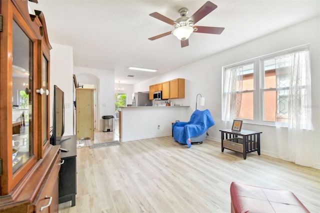 sitting room featuring ceiling fan with notable chandelier and light hardwood / wood-style flooring