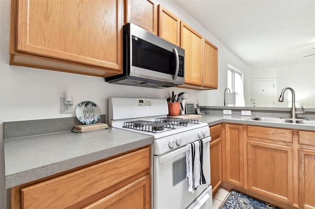 kitchen with white gas range, sink, and light tile patterned floors