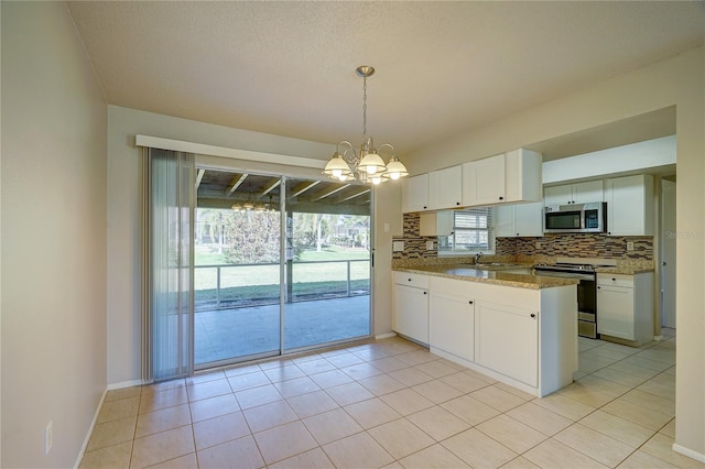 kitchen featuring white cabinetry, light stone countertops, backsplash, decorative light fixtures, and appliances with stainless steel finishes