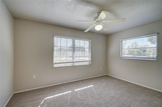 spare room with a textured ceiling, carpet floors, a wealth of natural light, and ceiling fan