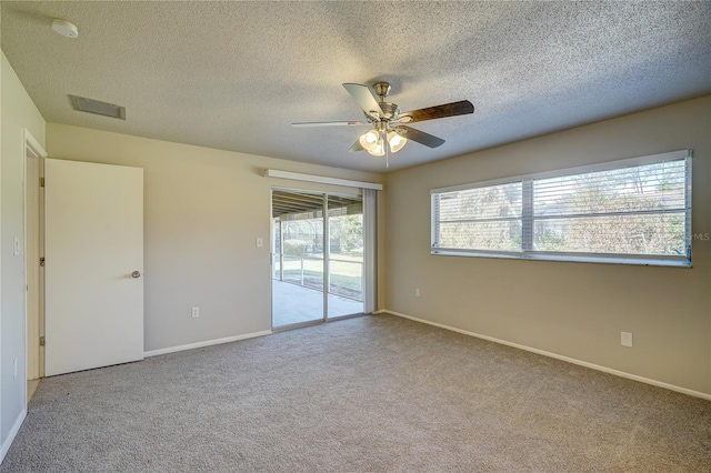 empty room featuring ceiling fan, light carpet, and a textured ceiling