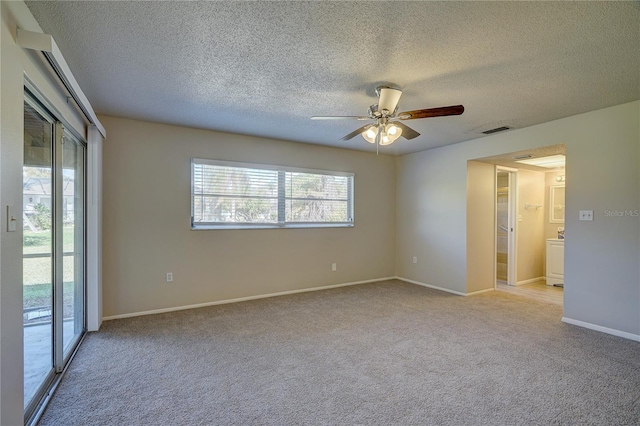 spare room with ceiling fan, light carpet, and a textured ceiling