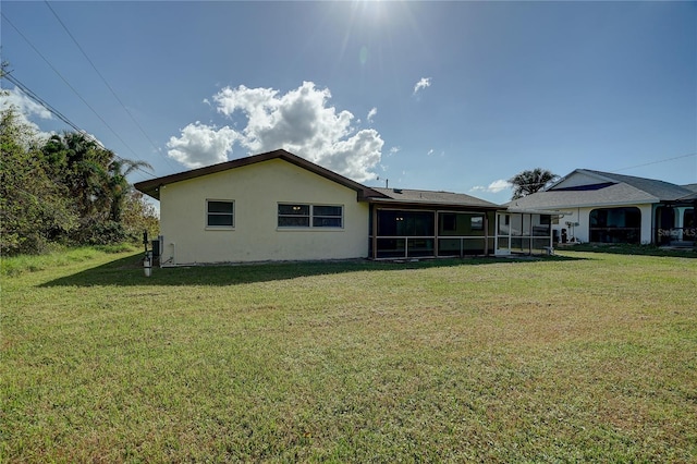 rear view of property featuring a lawn and a sunroom