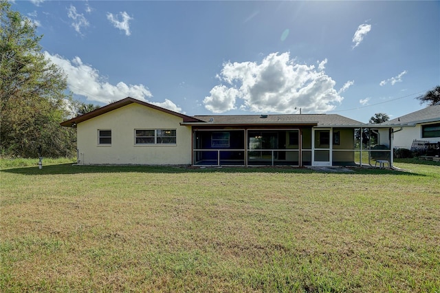 rear view of house featuring a lawn and a sunroom