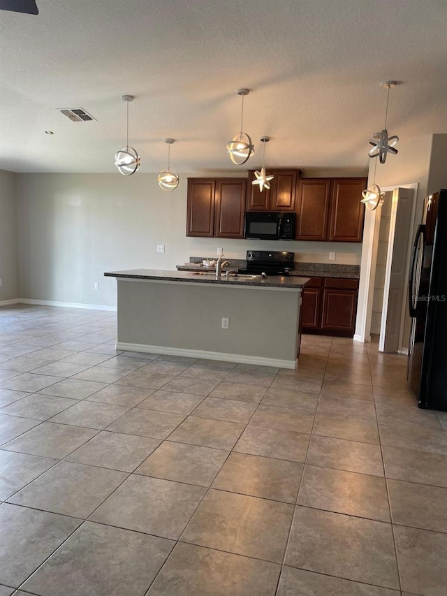 kitchen featuring black appliances, a textured ceiling, dark brown cabinets, hanging light fixtures, and a kitchen island with sink