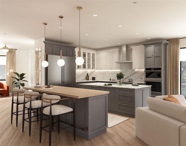 7176 S Shore Dr, South Pasadena, FL 33707 - kitchen with a center island with sink, stainless steel appliances, gray cabinetry, wall chimney exhaust hood, and backsplash