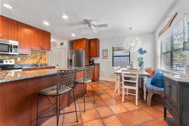 kitchen featuring light stone counters, sink, tasteful backsplash, a breakfast bar, and appliances with stainless steel finishes