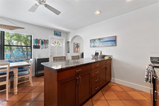 kitchen featuring dark stone counters, a textured ceiling, dark tile patterned floors, and kitchen peninsula