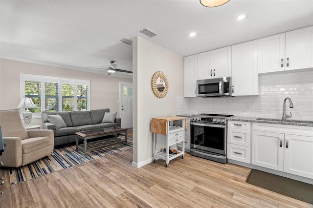 kitchen with stainless steel appliances, sink, light hardwood / wood-style floors, white cabinets, and ceiling fan