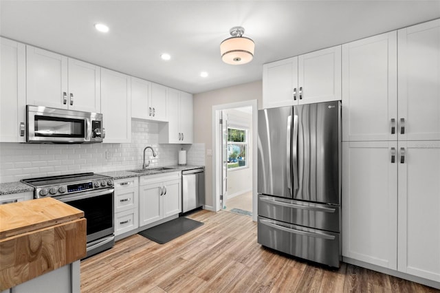 kitchen with light hardwood / wood-style floors, white cabinetry, sink, and appliances with stainless steel finishes