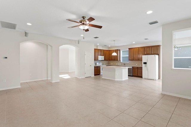 kitchen with pendant lighting, white appliances, backsplash, ceiling fan, and a kitchen island