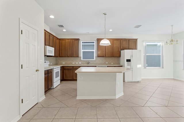 kitchen featuring pendant lighting, white appliances, a center island, and light tile patterned flooring