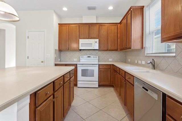 kitchen with decorative backsplash, sink, light tile patterned floors, and white appliances