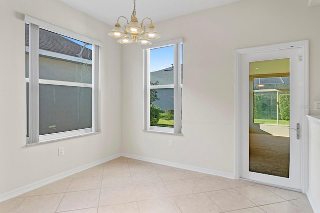 tiled empty room featuring an inviting chandelier