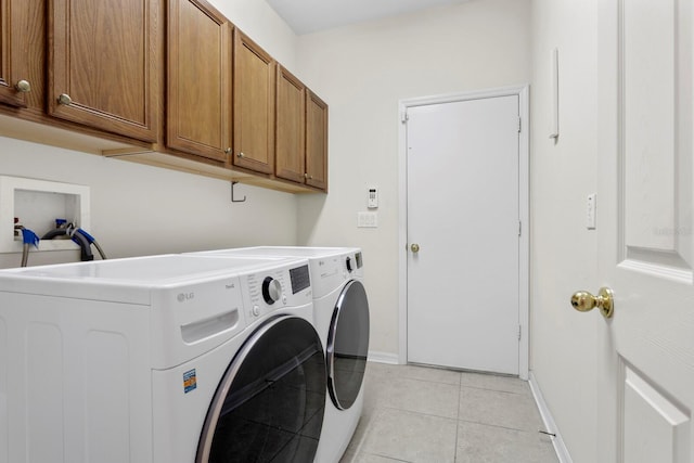 laundry area with cabinets, independent washer and dryer, and light tile patterned floors