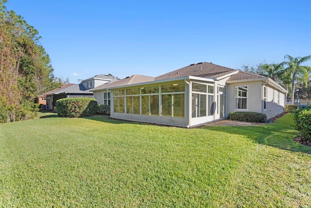 rear view of house with a lawn and a sunroom