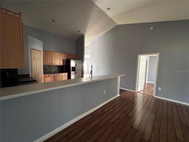 kitchen featuring stainless steel fridge, dark hardwood / wood-style floors, decorative backsplash, and kitchen peninsula