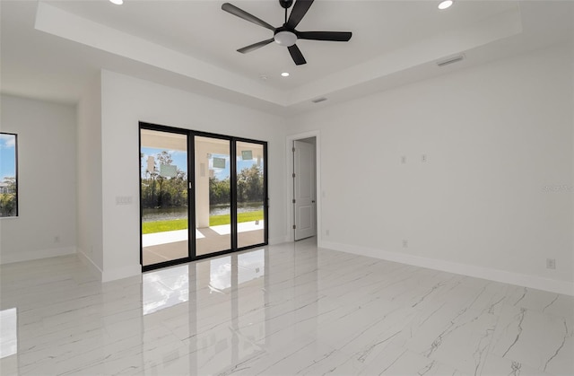 empty room featuring ceiling fan and a raised ceiling