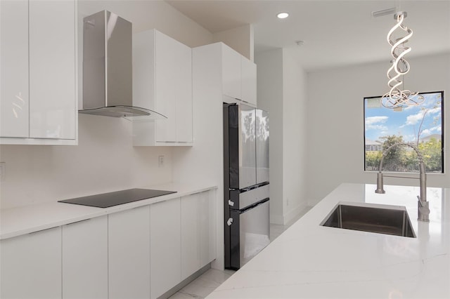 kitchen with black electric cooktop, white cabinets, wall chimney exhaust hood, sink, and stainless steel refrigerator