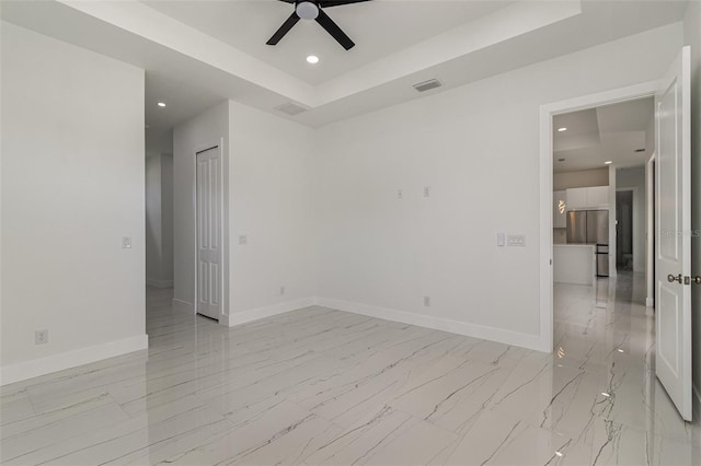 empty room featuring ceiling fan and a tray ceiling