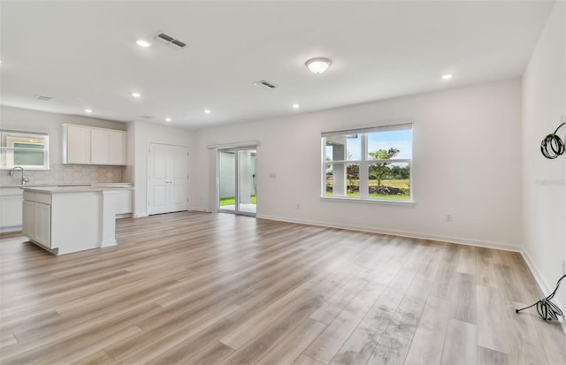 unfurnished living room with light hardwood / wood-style floors and sink