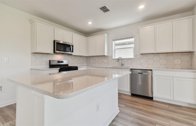 kitchen with stainless steel appliances, light hardwood / wood-style floors, white cabinetry, and sink