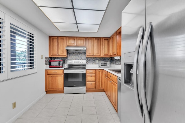 kitchen with appliances with stainless steel finishes, tasteful backsplash, and light tile patterned floors