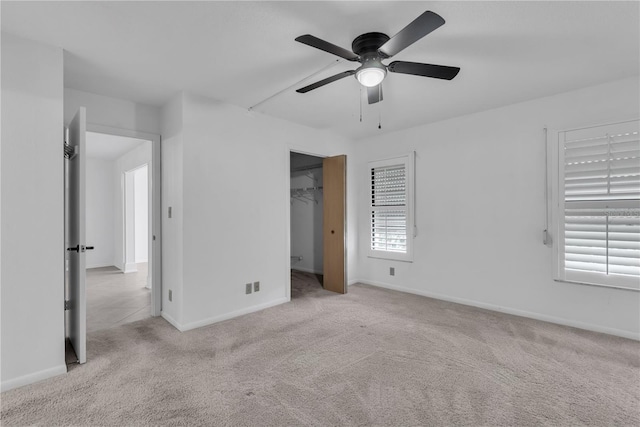 unfurnished bedroom featuring multiple windows, light carpet, a closet, and ceiling fan