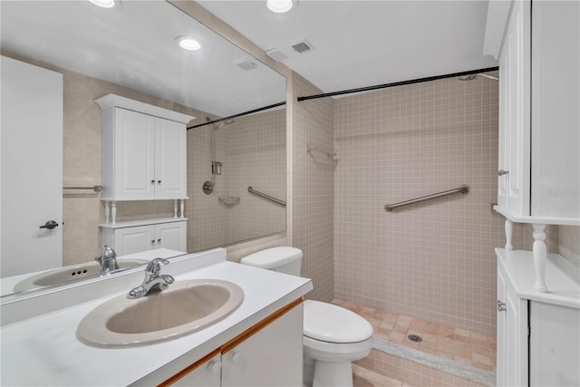 bathroom with vanity, toilet, and a tile shower