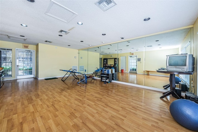 exercise room with hardwood / wood-style floors and a textured ceiling