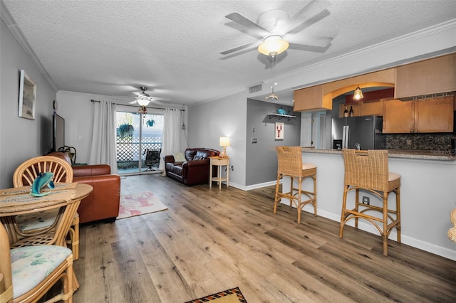 living room featuring a textured ceiling, light hardwood / wood-style floors, and ornamental molding