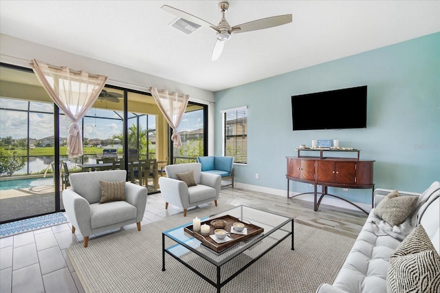 living room with ceiling fan, a water view, and light hardwood / wood-style flooring