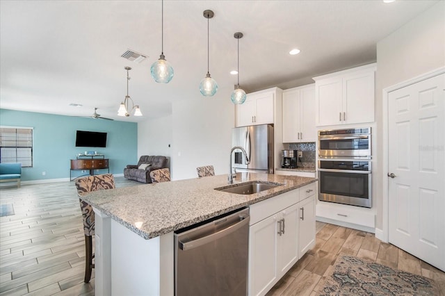 kitchen with white cabinets, stainless steel appliances, and a center island with sink