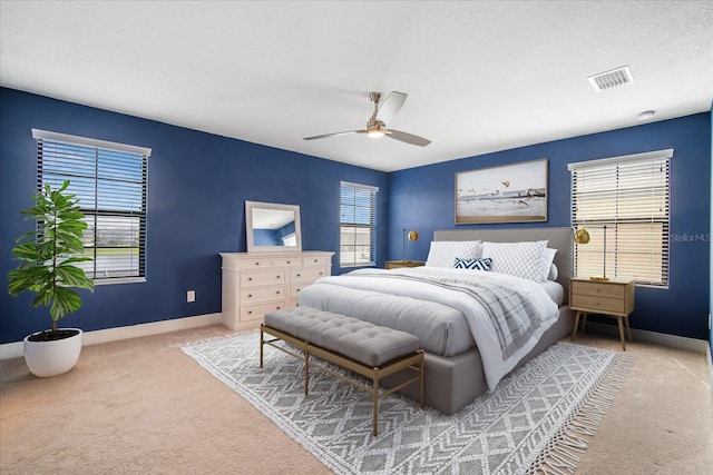 carpeted bedroom with ceiling fan, multiple windows, and a textured ceiling