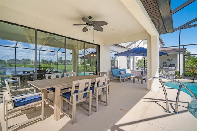 view of patio / terrace with ceiling fan, glass enclosure, and a water view