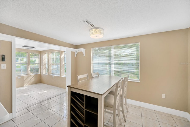 unfurnished dining area with a textured ceiling and light tile patterned floors