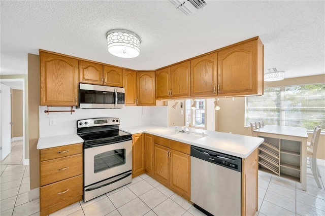 kitchen featuring kitchen peninsula, a textured ceiling, sink, light tile patterned floors, and appliances with stainless steel finishes