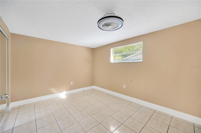 tiled empty room with a textured ceiling