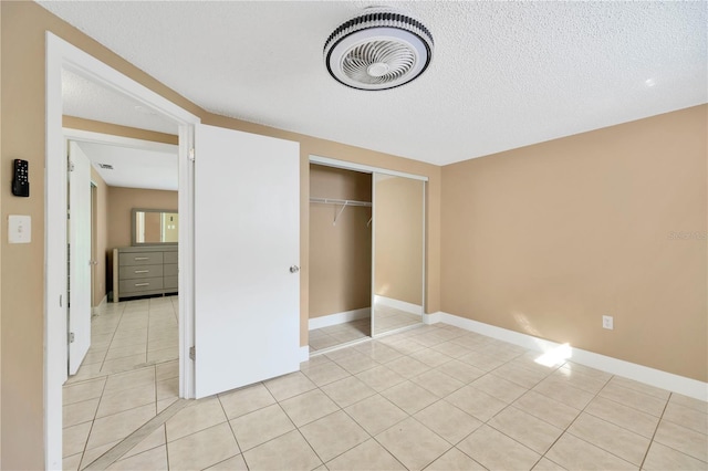 unfurnished bedroom featuring light tile patterned floors, a textured ceiling, and a closet