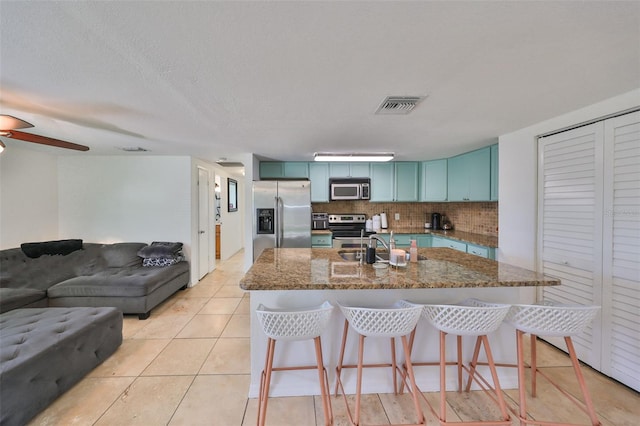 3207 Acacia St, Lutz, FL 33558 - kitchen featuring stainless steel appliances, open floor plan, a breakfast bar area, dark stone countertops, and backsplash