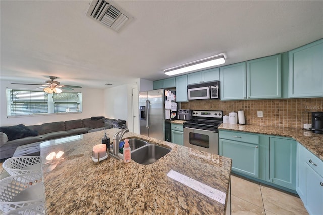 3207 Acacia St, Lutz, FL 33558 - kitchen featuring stainless steel appliances, a sink, light stone counters, decorative backsplash, and open floor plan