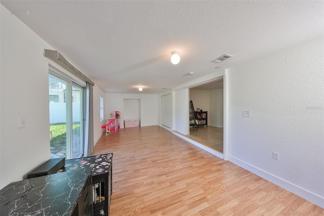 3207 Acacia St, Lutz, FL 33558 - hallway with light wood-style floors, a textured ceiling, a textured wall, and baseboards
