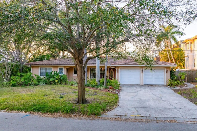 ranch-style house with driveway, a tiled roof, a front yard, and stucco siding