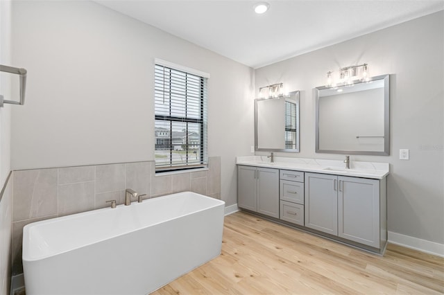 bathroom with hardwood / wood-style floors, vanity, and a tub to relax in